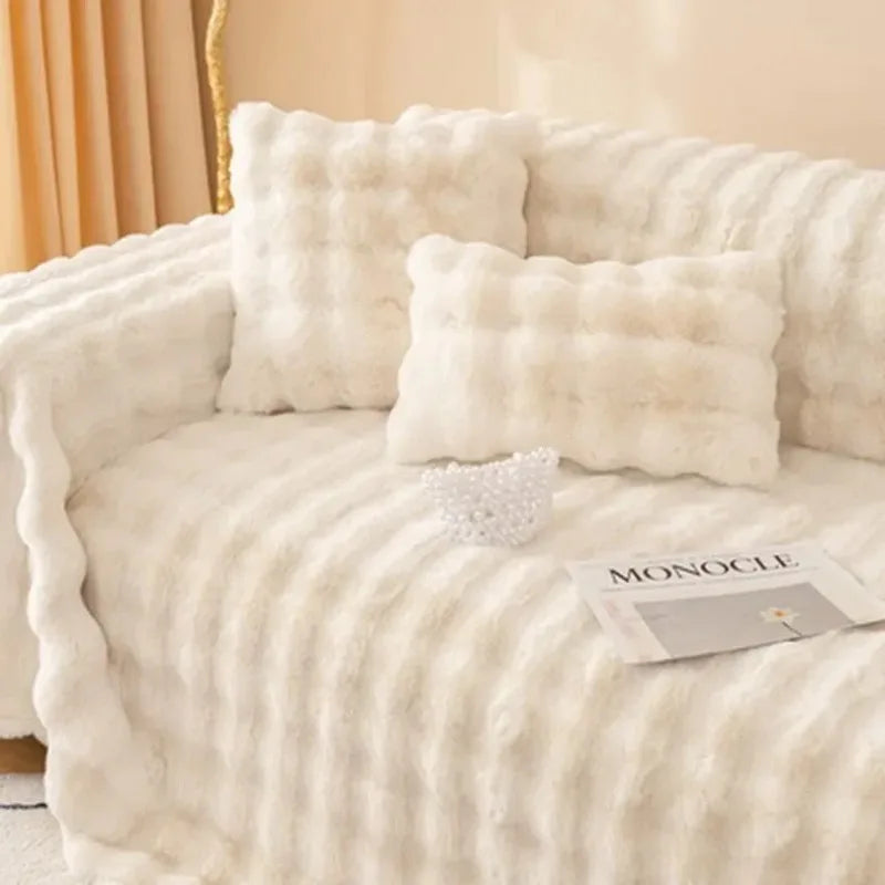 Fluffy white blanket draped over a sofa with pillows and a magazine.