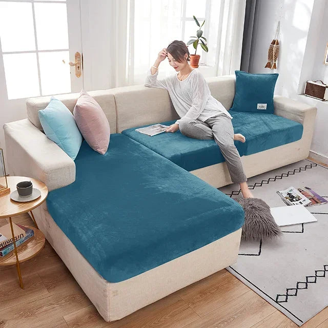 Woman sitting on a sectional sofa with blue cushions in a bright living room.