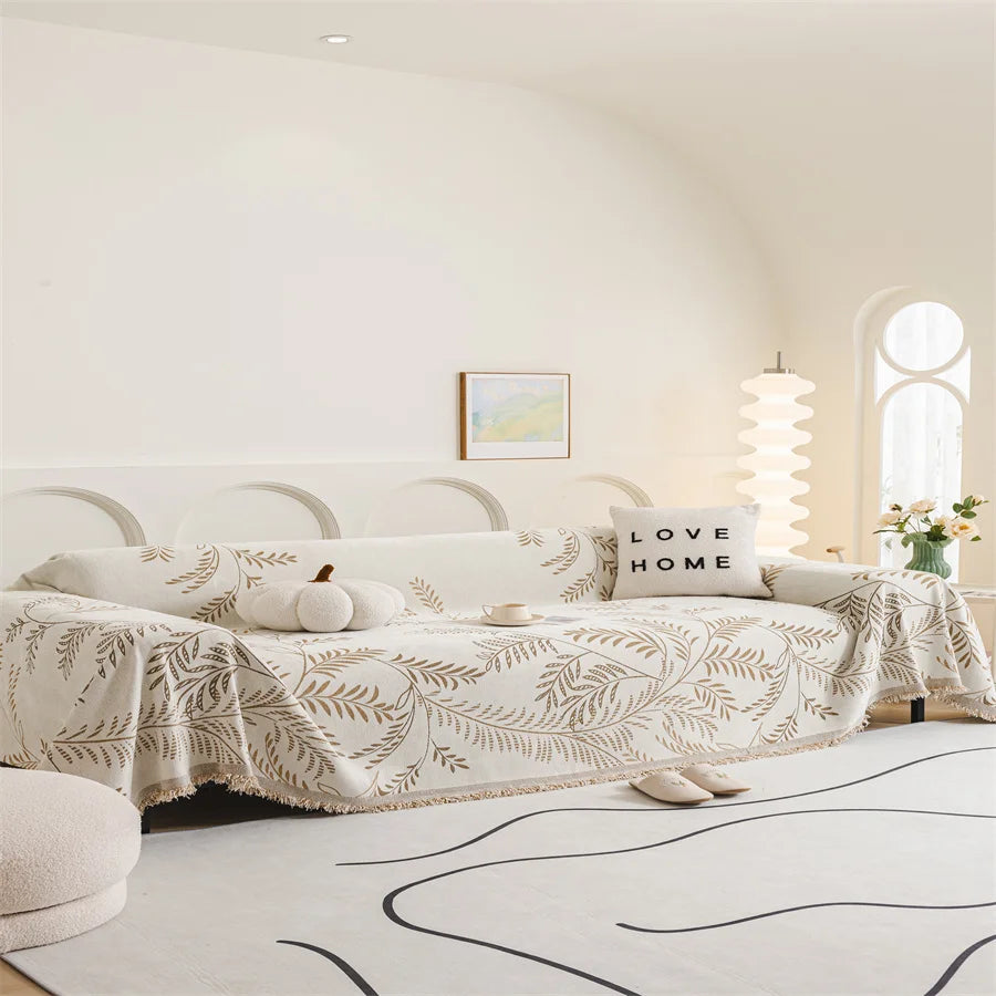 Modern living room with a sofa covered by a patterned throw blanket, 'Love Home' pillow, and decorative items.