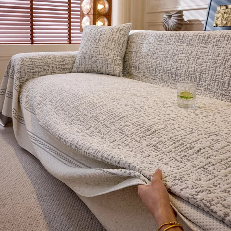 Person adjusting a textured beige sofa cover on a couch.