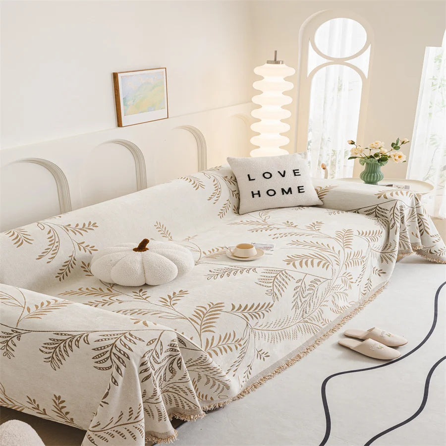 Neatly made bed with a decorative blanket and 'Love Home' pillow in a bright bedroom.
