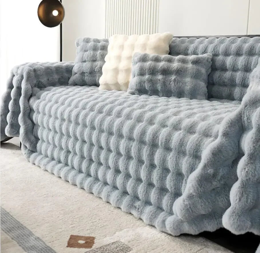 Fluffy grey throw blanket draped over a sofa in a living room setting.