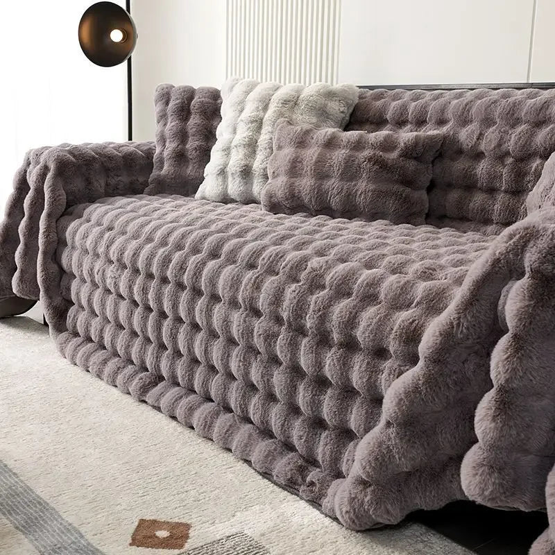 Grey plush faux rabbit bubble blanket draped over a sofa in a living room setting.
