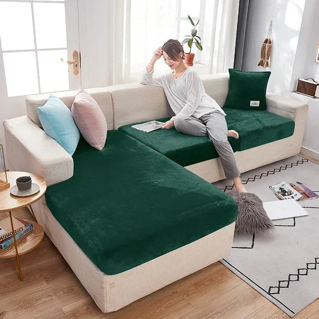 Woman sitting on a sectional sofa with green cushions in a bright living room.