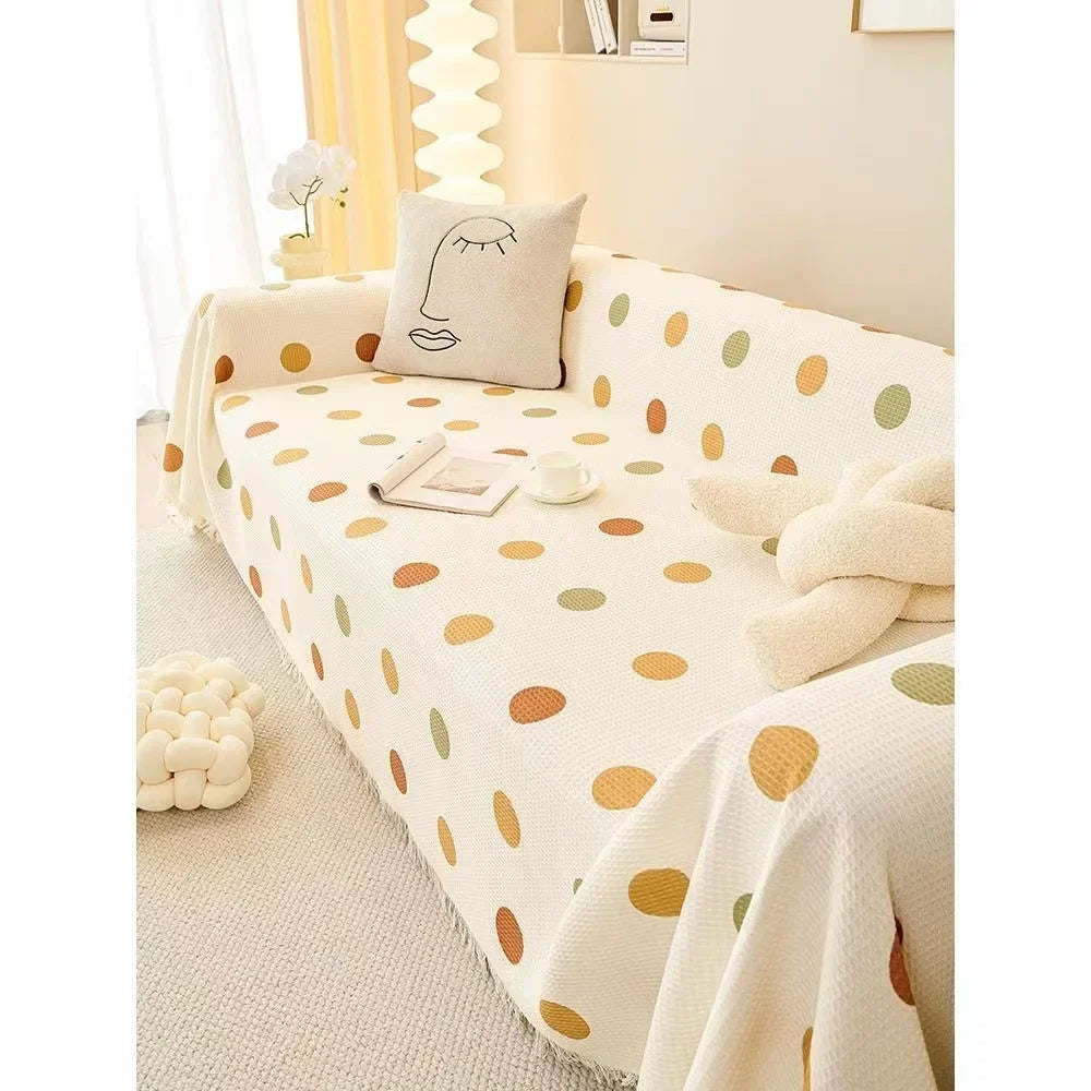 Polka dot blanket draped over a couch with a pillow in a cozy room.