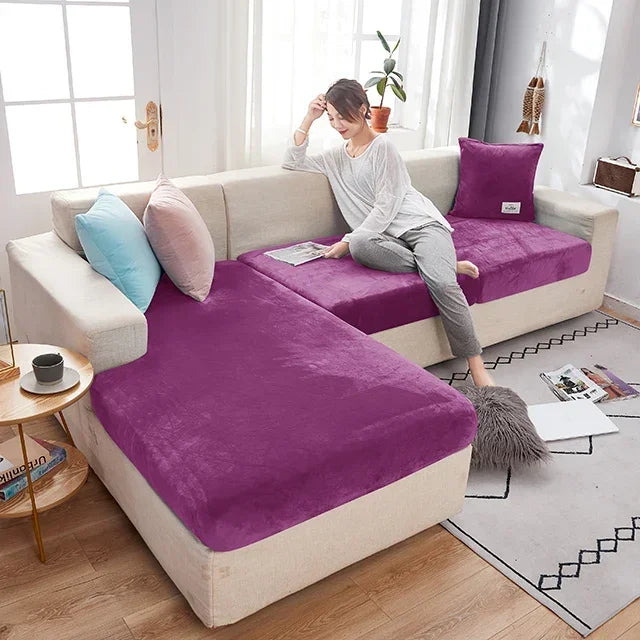 Woman sitting on a purple and beige sectional sofa in a living room.