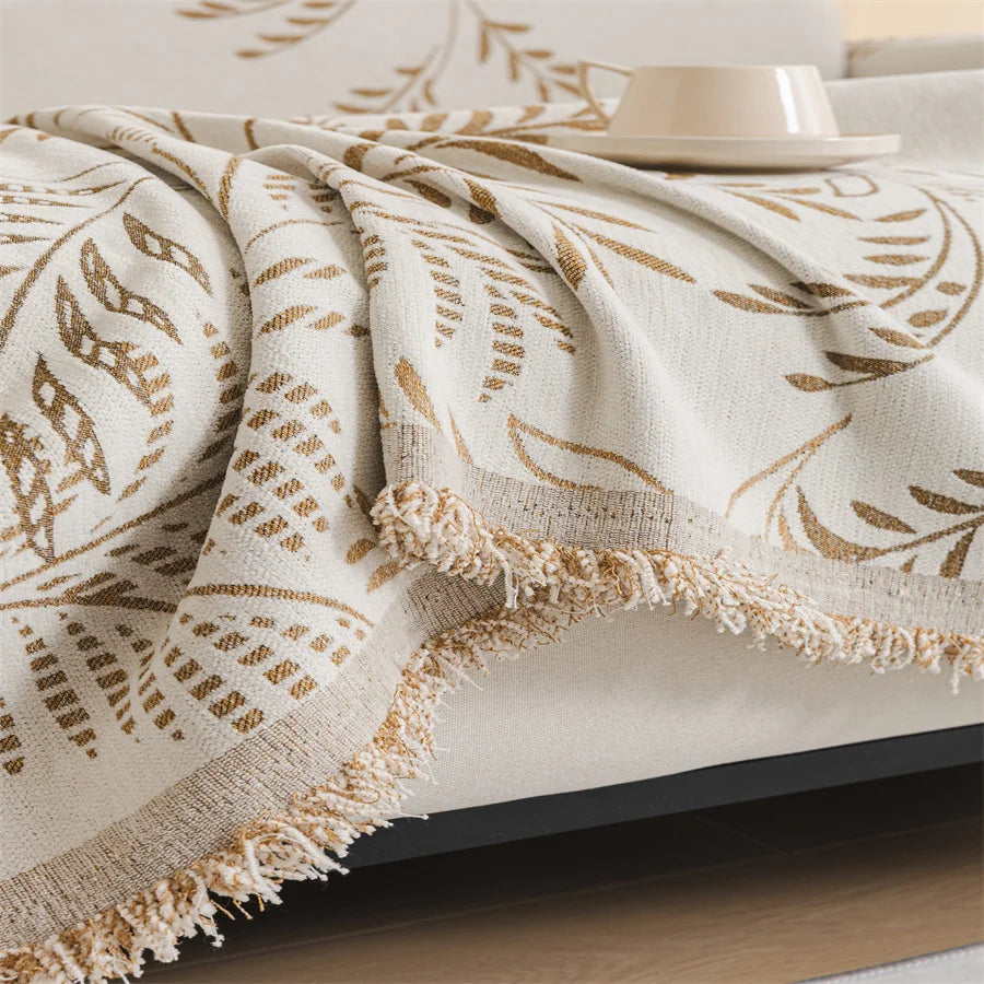 Beige and brown patterned blanket on a bed with a white pillow and plate.