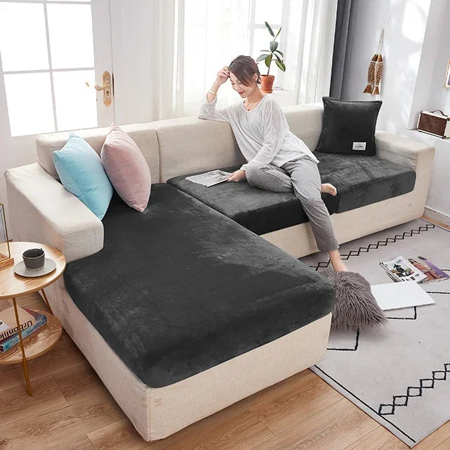Woman sitting on a sectional sofa with dark cushions in a bright living room.