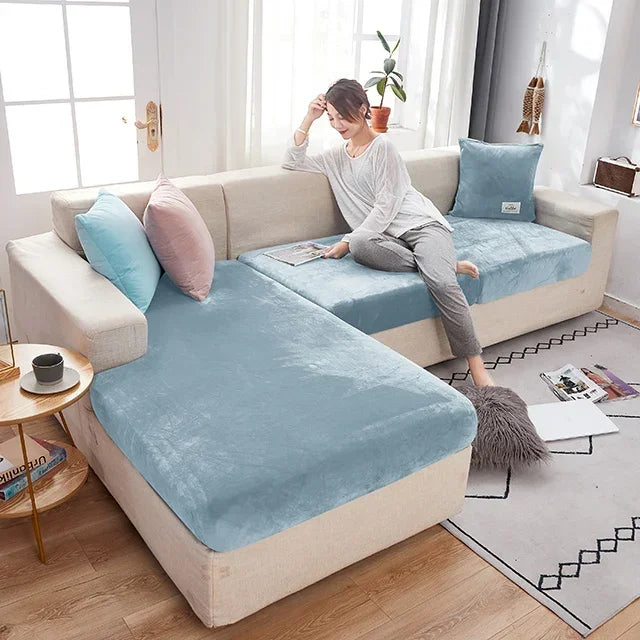 Woman sitting on a sectional sofa with blue cushions in a bright living room.
