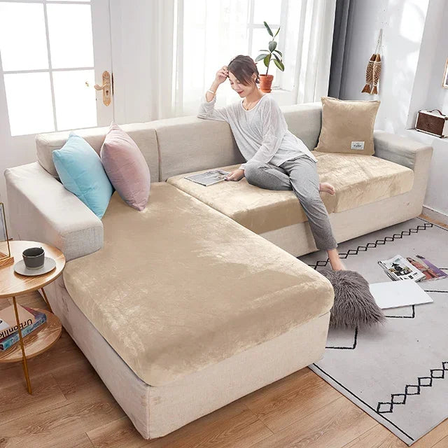 Woman sitting on a beige sectional sofa in a bright living room.