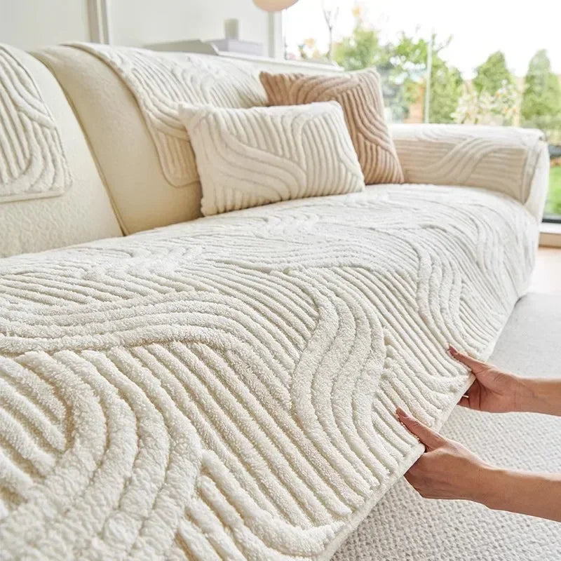 Beige textured throw blanket being draped over a sofa in a bright living room.