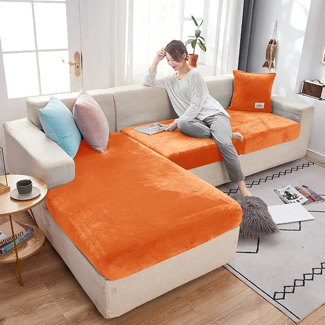 Woman sitting on a sectional sofa with orange cushions in a living room.