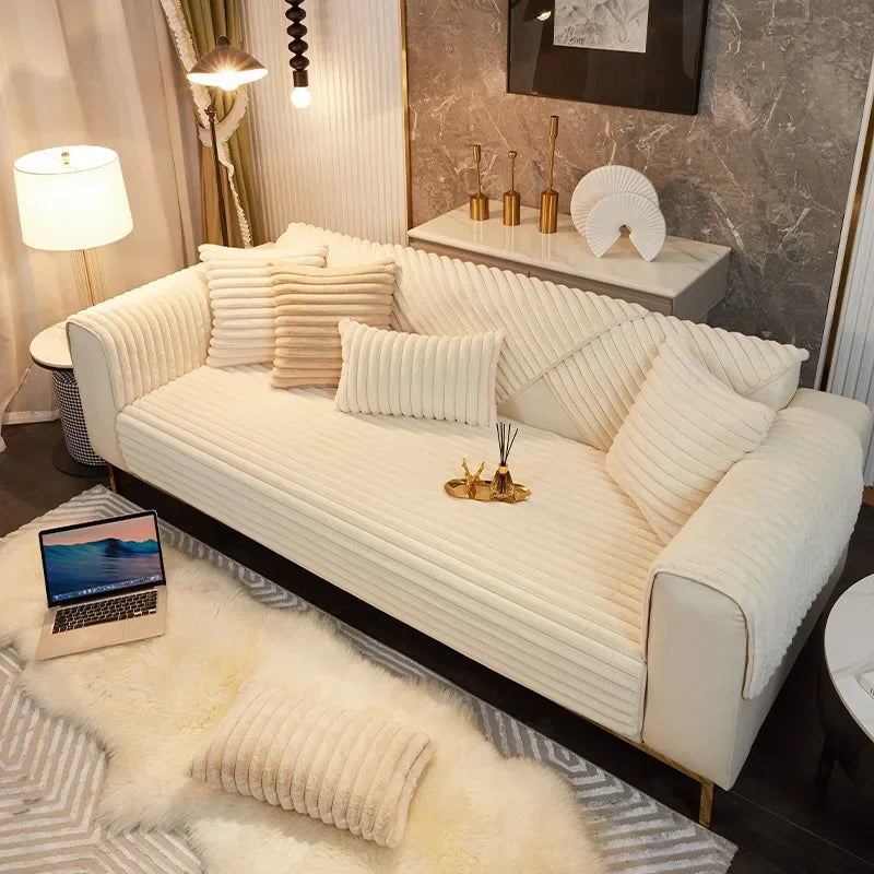 Modern living room with a plush white sofa cover, laptop, and decorative items.