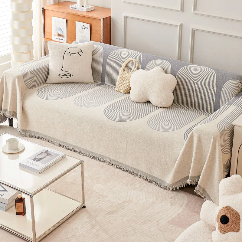 Sofa with a decorative throw blanket and pillows in a living room setting.