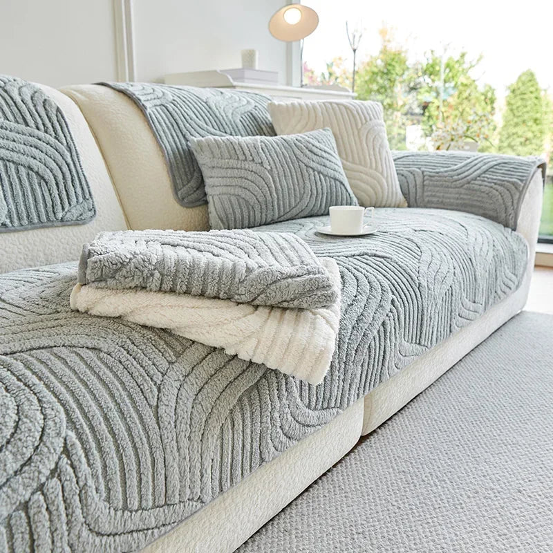 Grey textured sofa cover on a white sofa with decorative pillows and a blanket in a bright living room.