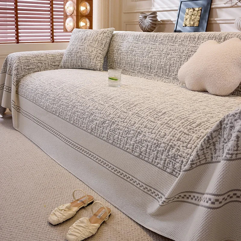 Beige sofa with patterned cover and decorative pillows in a living room setting.