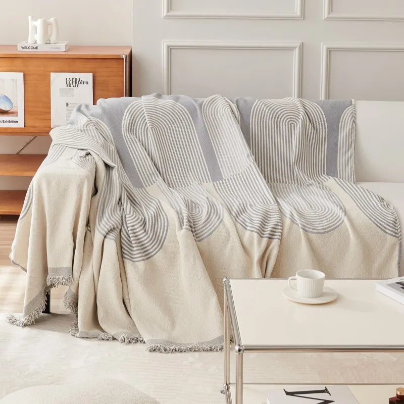 Beige and gray patterned throw blanket draped over a sofa in a living room setting.