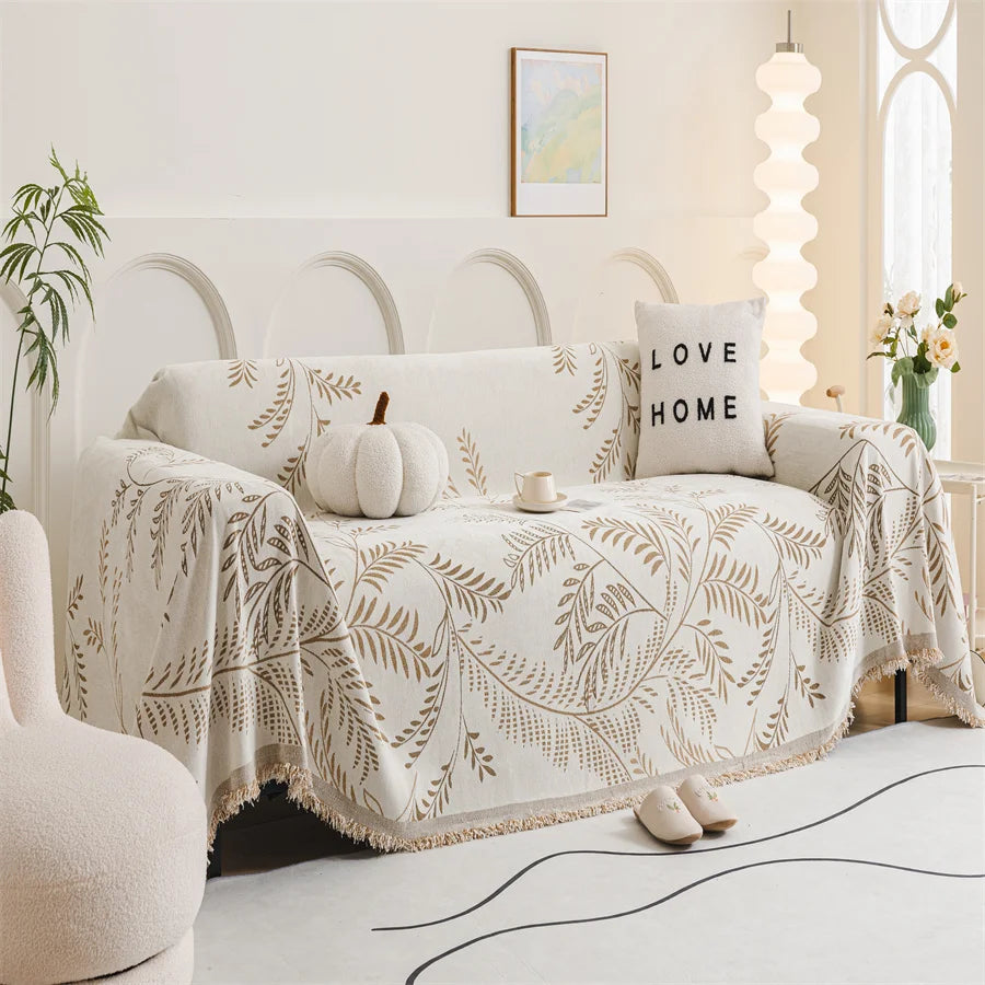 Living room with a sofa covered by a patterned throw blanket, decorative pillows, and a small table.