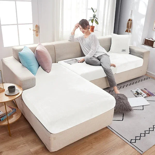 Woman sitting on a beige sectional sofa with white mattress cover in a bright living room.