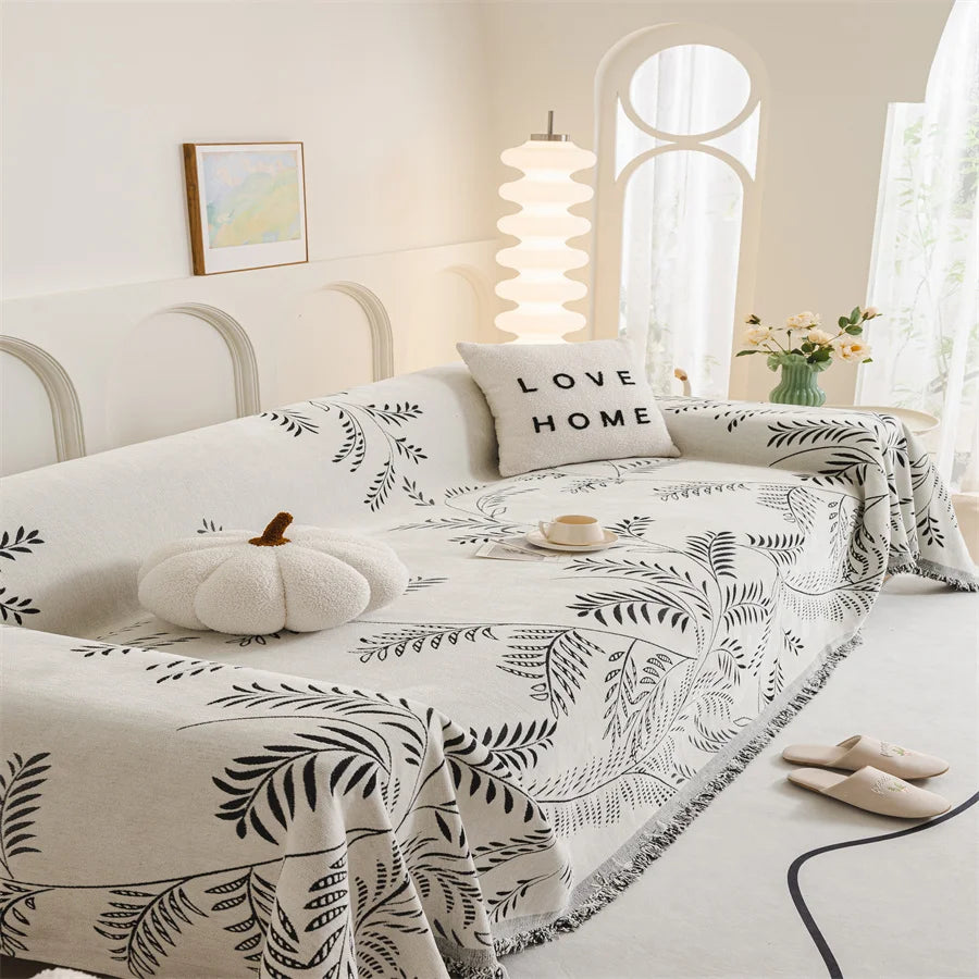 Bedroom with a bed covered in a leaf-patterned comforter, white pillows, and decorative items.