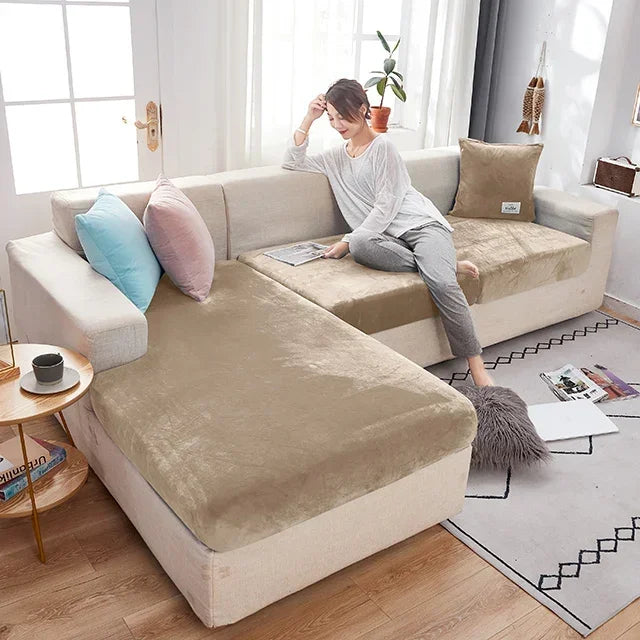 Woman sitting on a beige sectional sofa with brown seat covers in a bright living room.