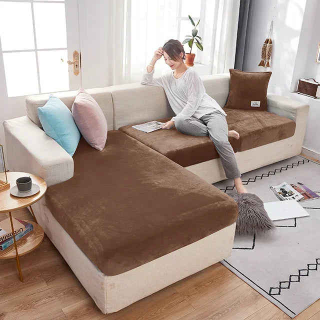 Woman sitting on a sectional sofa with brown and beige cushions in a bright living room.